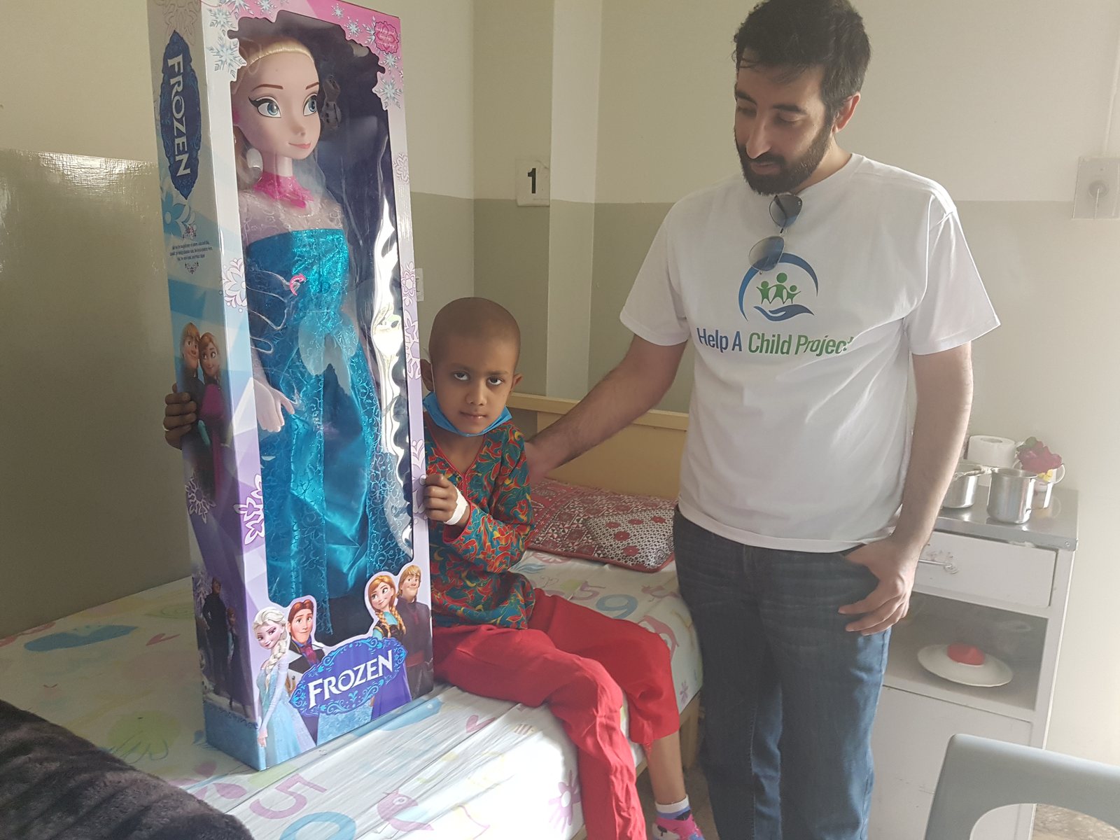 Kaiser Khan delivering a gift to a child during a Help A Child Project hospital visit